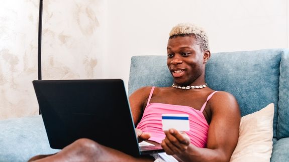 Schwarze transsexuelle Person, die zu Hause Online-Einkäufe mit Kreditkarte tätigt